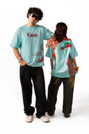 Sollzz Umbra SeaJet Oversize Tee in light blue featuring a male model in front with red "Tamsik" chest typography and a female model from behind displaying the red and teal graphic mask back print