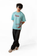 A model wearing a Sollzz light blue graphic t-shirt with red text and a red bird design, paired with black jeans and beige sneakers, standing against a white studio background.