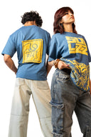 Sollzz Noctra - Silent Watcher Oversize Tee in dark navy blue featuring a male model from behind displaying the square yellow abstract art back patch and a female model from the front in yellow Sollzz block typography and tiger artwork, styled with light washed denim